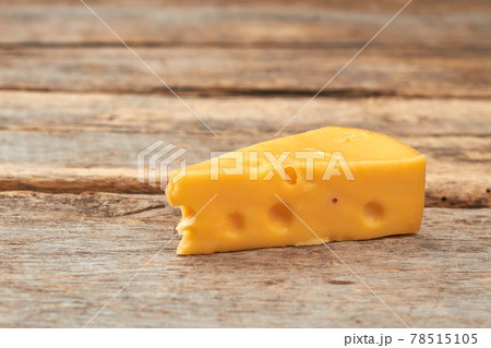Piece of swiss cheese on wooden background. 78515105