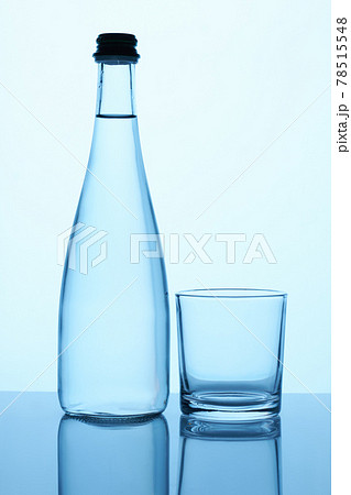 Glass bottle with liquid and glass cup. 78515548