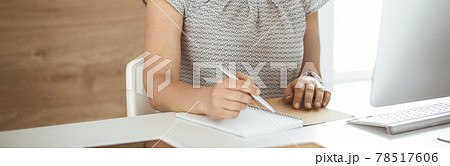 Unknown business woman working with computer while sitting at the desk in modern office, close-up. Middle aged female lawyer or auditor at work 78517606