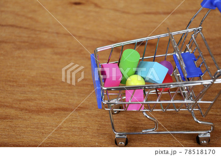 Colorful of rubber cube and other shapes inside toy shopping trolley with wood texture background. Colorful of rubber cube and other shapes inside toy shopping trolley with wood texture background. 78518170