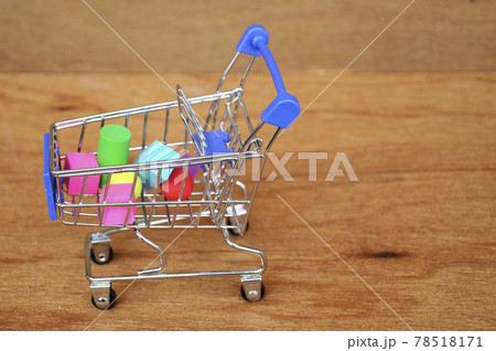 Colorful of rubber cube and other shapes inside toy shopping trolley with wood texture background. Colorful of rubber cube and other shapes inside toy shopping trolley with wood texture background. 78518171