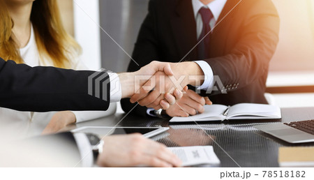 Businessman shaking hands with his colleague above the glass desk in sunny modern office, close-up. Unknown business people at meeting 78518182