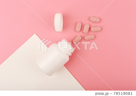 Creative flat lay with nutritional supplement or vitamins for woman. Opened medication bottle on pink background Creative flat lay with nutritional supplement or vitamins for woman. Opened medication bottle on pink background 78519081