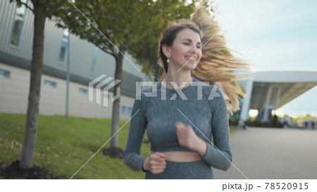 Young woman runner training in summer park city. Portrait of young and fit woman running and jogging alone on the empty street in city center wearing protective. Slow-motion shot Young woman runner training in summer park city. Portrait of young and fit woman running and jogging alone on the empty street in city center wearing protective. Slow-motion shot 78520915