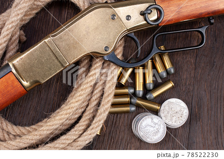 Old west gun - lever-action repeating rifle with bullets and silver dollar coins 78522230
