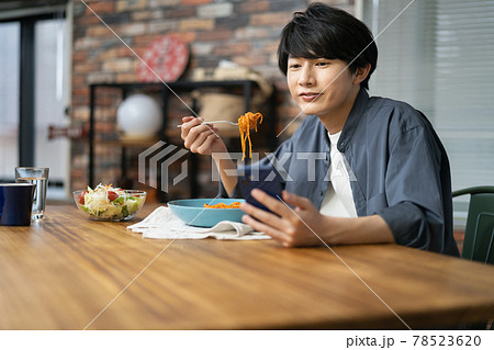 食事中にスマホを見る若い男性 78523620