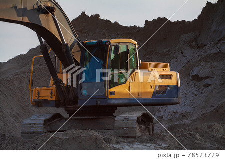 Yellow excavator on a construction site against blue sky Yellow excavator on a construction site against blue sky 78523729