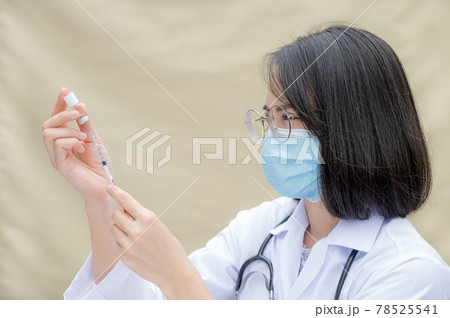The doctor's holding a syringe and was about to vaccinate patient at the clinic to prevent the spread of the virus The doctor's holding a syringe and was about to vaccinate patient at the clinic to prevent the spread of the virus 78525541