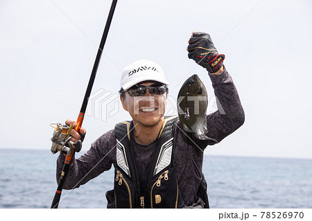 魚釣りでメジナを釣り上げた男性 78526970