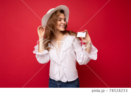 Shot of attractive positive smiling young dark blonde woman wearing white blouse and white hat 78528253