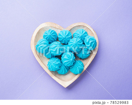 Heart shaped wooden dish with blue sweet meringues 78529983