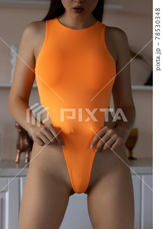 Crop seductive woman in bodysuit standing provocatively in light room 78530348