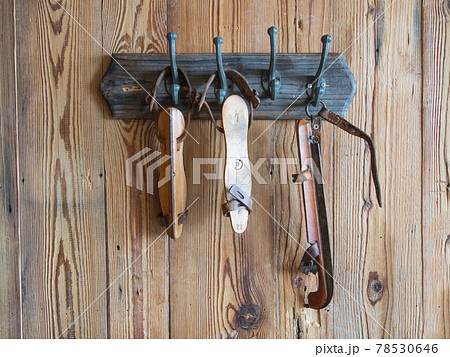 group of white old ice skates hanging on a wooden wall 78530646