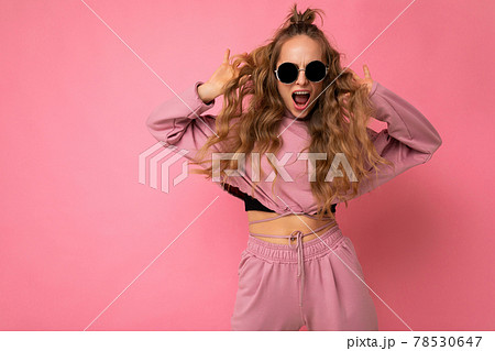 Shot of beautiful happy positive joyful young dark blonde curly woman isolated over pink background 78530647