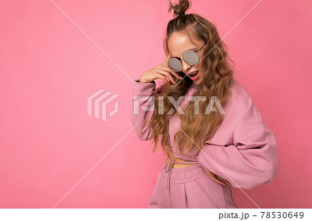 Shot of beautiful happy young dark blonde curly woman isolated over pink background wall wearing 78530649