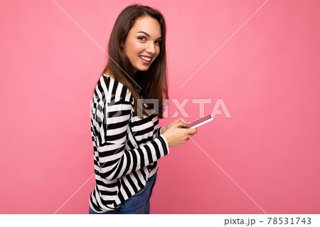 Beautiful young brunette woman using mobile phone communicating via texting message wearing sweater Beautiful young brunette woman using mobile phone communicating via texting message wearing sweater 78531743