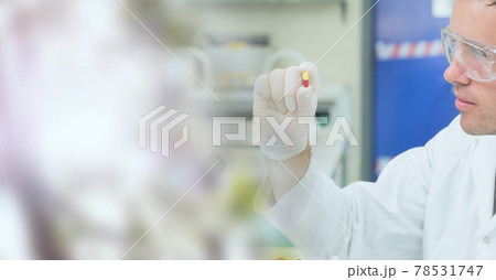 Composition of male scientist holding pill in laboratory with copy space 78531747