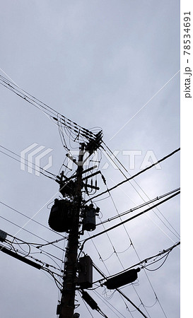 Looking upward to a utility pole with distribution transformers, in a residential area in Japan. 78534691