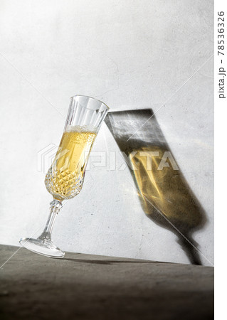 Champagne glass and long glass shadow against concrete wall 78536326