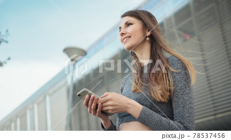 Close-up Of A Young Beautiful Sports Fitness Girl Holding A Smartphone In The Hands, Using A Fitness App. Modern City Shooting On the Street. Portrait woman looking at smartphone while running outdoor Close-up Of A Young Beautiful Sports Fitness Girl Holding A Smartphone In The Hands, Using A Fitness App. Modern City Shooting On the Street. Portrait woman looking at smartphone while running outdoor 78537456