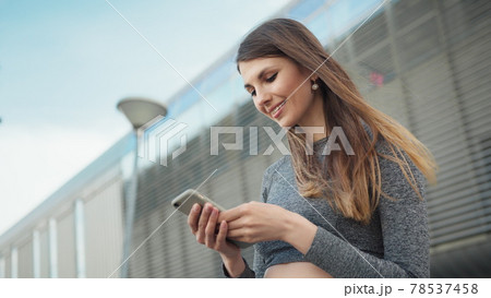 Close-up Of A Young Beautiful Sports Fitness Girl Holding A Smartphone In The Hands, Using A Fitness App. Modern City Shooting On the Street. Portrait woman looking at smartphone while running outdoor 78537458