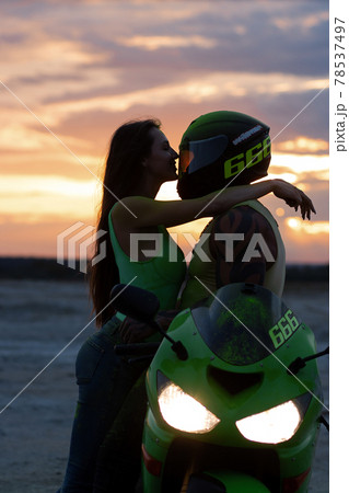 Couple embracing near motorbike on beach at sunset Couple embracing near motorbike on beach at sunset 78537497