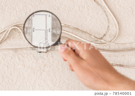 A worker's hand inspects a large antenna splitter with a magnifying glass, close-up A worker's hand inspects a large antenna splitter with a magnifying glass, close-up 78540001