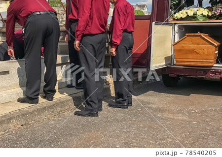 Porters lower the coffin into the grave in the cemetery 78540205