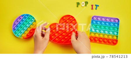 Kid hands playing with colorful pop It fidget toy. Colorful antistress sensory toy fidget push pop it. Kid hands playing with colorful pop It fidget toy. Colorful antistress sensory toy fidget push pop it. 78541213