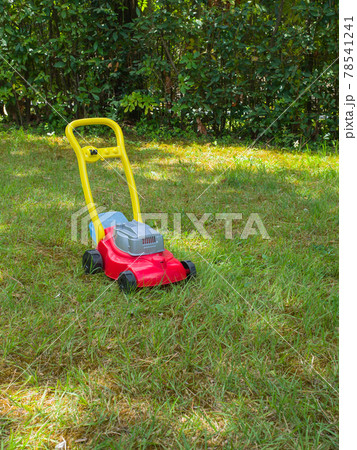Push lawn mower toy on the grass in a garden . No people Push lawn mower toy on the grass in a garden . No people 78541241