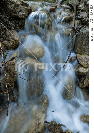 Small beautiful waterfall with stones and small branches in dusk Small beautiful waterfall with stones and small branches in dusk 78542382