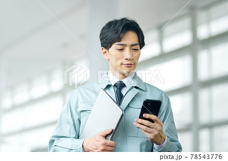 オフィスで働くスマホを操作する作業服のエンジニア 78543776