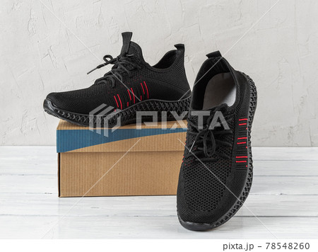 Side view of modern breathable sneakers on a brown cardboard box. 78548260