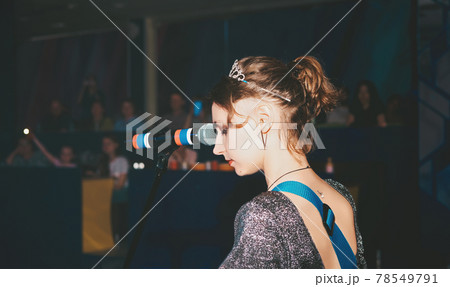 young female caucasian singer performing a song on a stage. singing woman, emotional passionate vocalist. rock music public concert. rear view 78549791