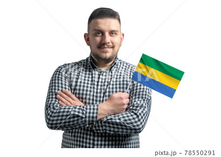 White guy holding a flag of Gabon smiling confident with crossed arms isolated on a white background 78550291