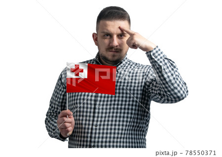 White guy holding a flag of Tonga and a finger touches the temple on the head isolated on a white background White guy holding a flag of Tonga and a finger touches the temple on the head isolated on a white background 78550371