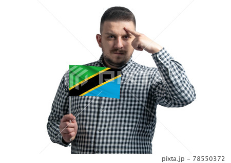 White guy holding a flag of Tanzania and a finger touches the temple on the head isolated on a white background White guy holding a flag of Tanzania and a finger touches the temple on the head isolated on a white background 78550372
