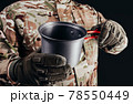 Soldier in gloves holding metal dish cup. 78550449