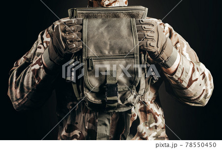Soldier in gloves holding tactical leg bag. Soldier in gloves holding tactical leg bag. 78550450