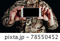 Soldier in gloves holding smartphone. 78550452