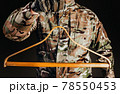 Soldier in gloves holding wooden shirt hanger. 78550453