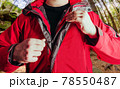 Man putting on travel hiking red jacket in woods. 78550487