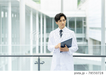 病院でカルテを見る白衣の若い医者の写真素材