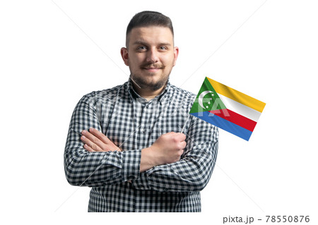 White guy holding a flag of Comoros smiling confident with crossed arms isolated on a white background 78550876