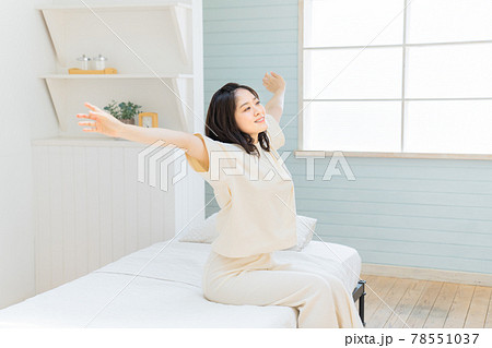 朝に起きて伸びをする若い女性 78551037