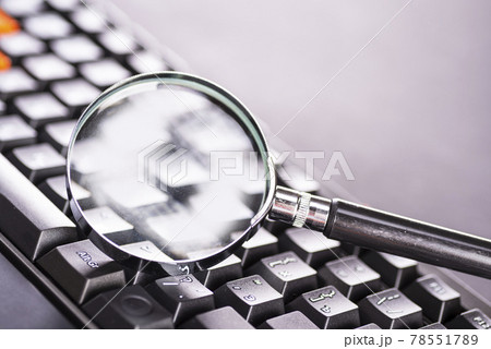 Closeup images of magnifying glass on laptop keyboard 78551789