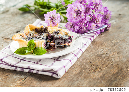 blueberry tartlet on a plate and purple flowers blueberry tartlet on a plate and purple flowers 78552896
