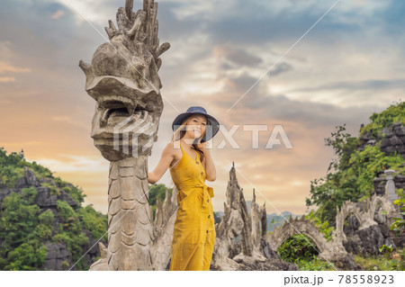 Woman tourist on background of amazing huge dragon statue at limestone mountain top near Hang Mua view point at foggy morning. Popular tourist attraction at Tam Coc, Ninh Binh. Vietnam travel Woman tourist on background of amazing huge dragon statue at limestone mountain top near Hang Mua view point at foggy morning. Popular tourist attraction at Tam Coc, Ninh Binh. Vietnam travel 78558923