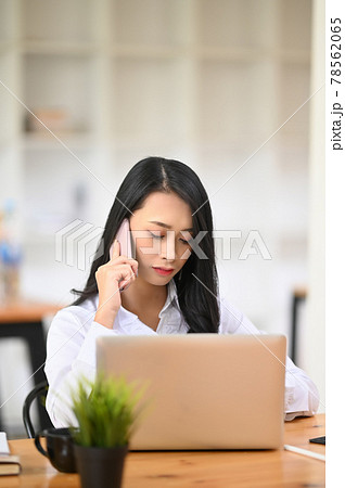 Young woman calling with mobile phone and sitting at office desk. Young woman calling with mobile phone and sitting at office desk. 78562065