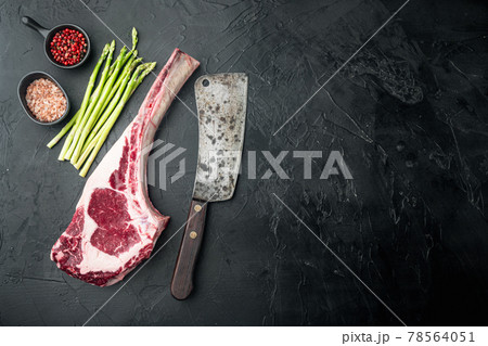 Classic fresh beef striploin steaks,Tomahawk cut, on black stone background, top view flat lay, with copy space for text 78564051